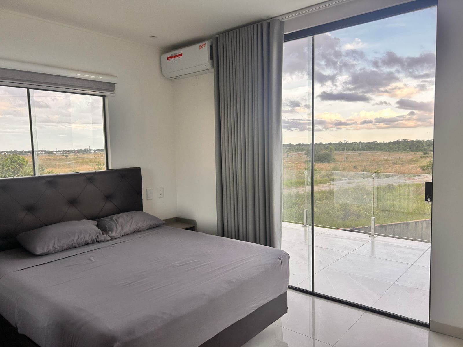A bedroom with a private balcony opening onto open sunset views